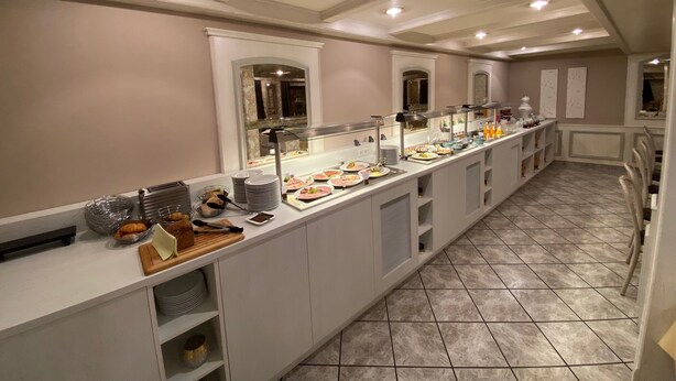 A buffet setup with a variety of food items and a long counter. - Hotel Zum Adler (Nidderau)