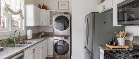 A modern kitchen with stainless steel appliances, a double oven, and a built-in washer and dryer.