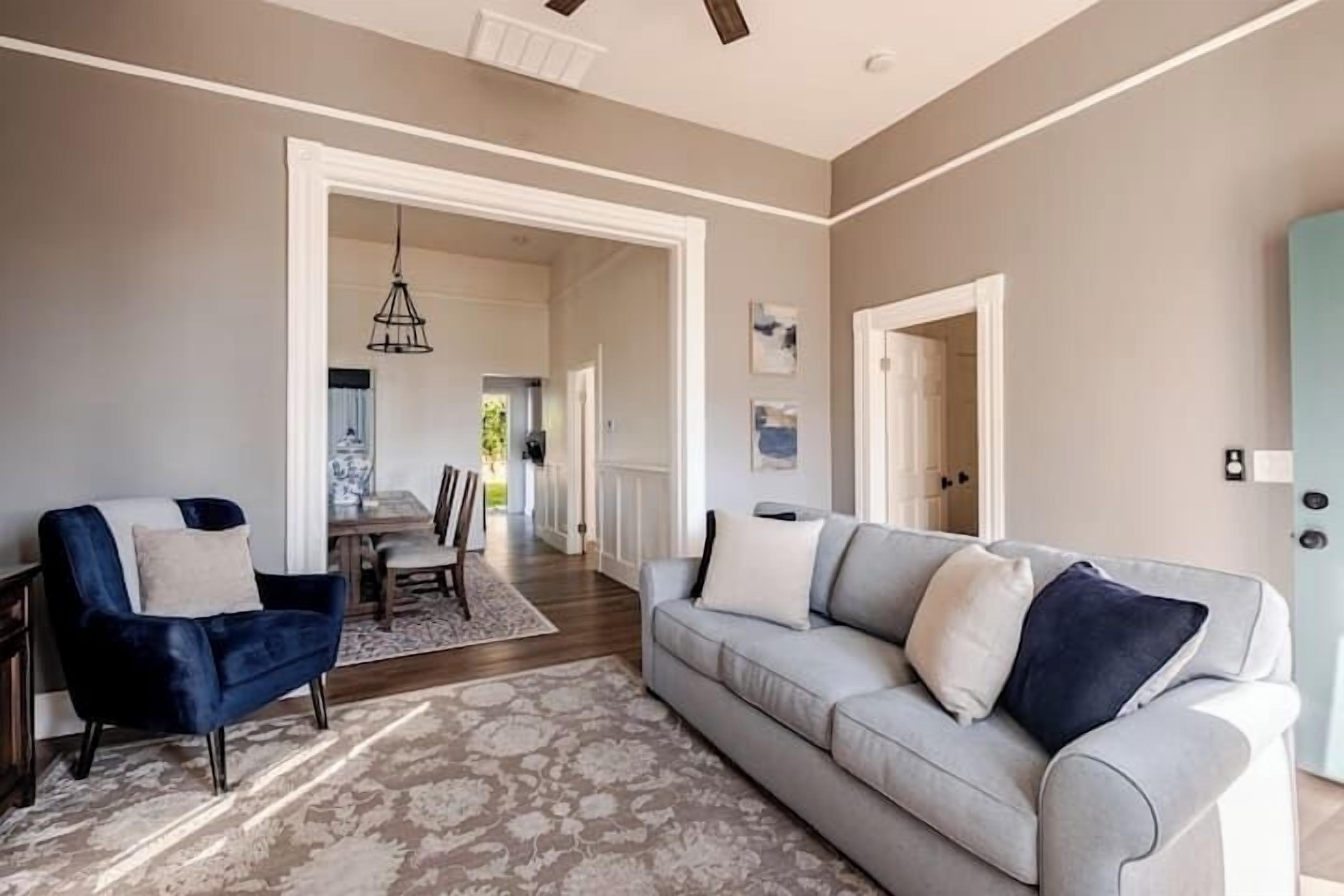 A living room with a light grey sofa, a dark blue armchair, and a patterned rug.
