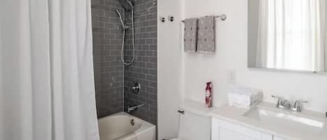 Un baño moderno con bañera, ducha, inodoro y lavamanos.