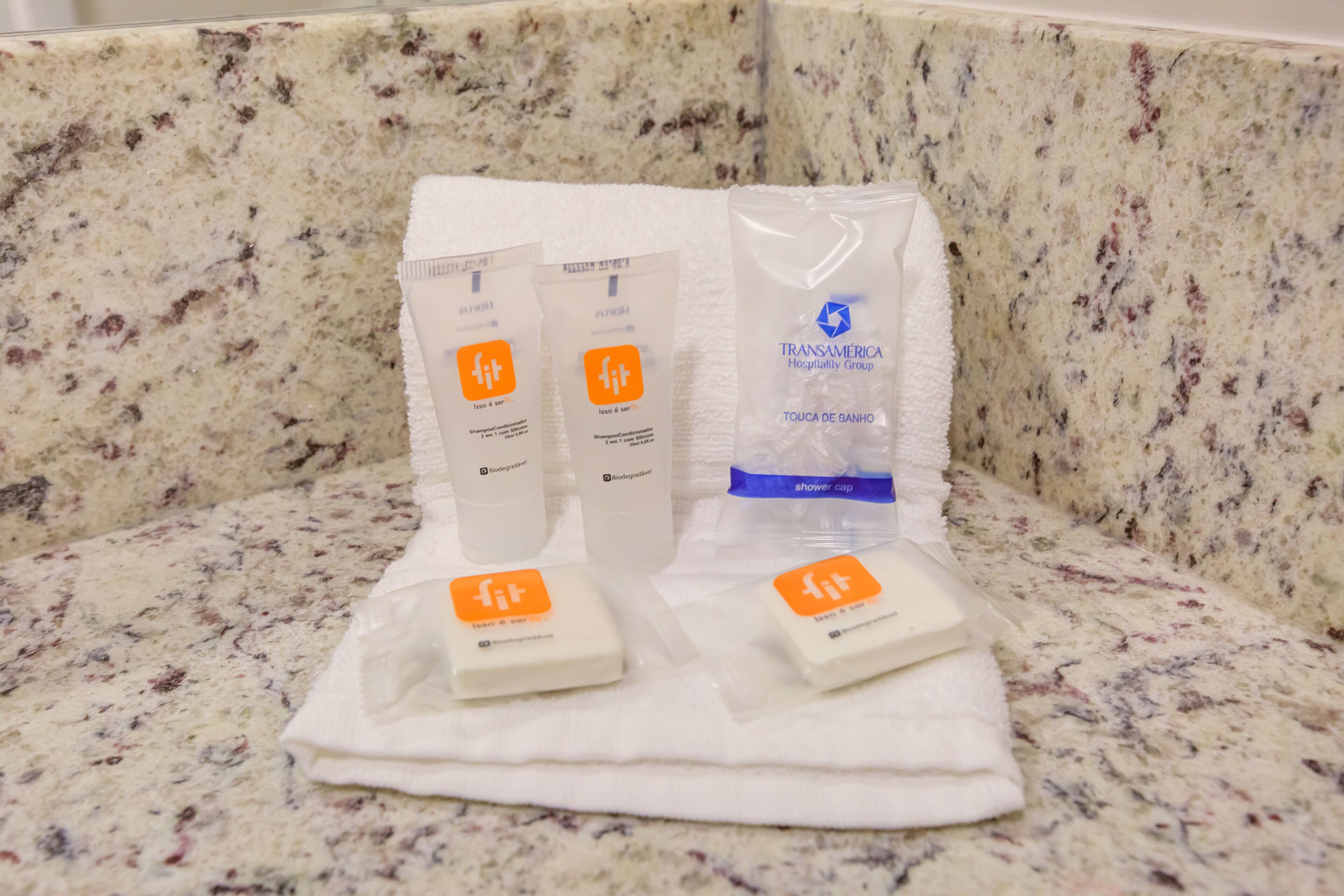 A bathroom counter with toiletries including shampoo, conditioner, and a shower cap.