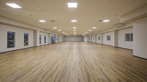 A spacious room with a wooden floor, white walls, and multiple windows.