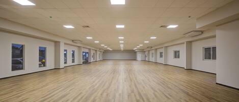 A spacious room with a wooden floor, white walls, and multiple windows.