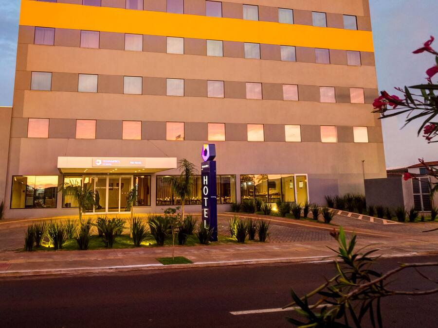 Un Hotel Transamerica Fit con diseño moderno, que presenta una llamativa banda amarilla a lo largo de la fachada y una entrada bien iluminada.