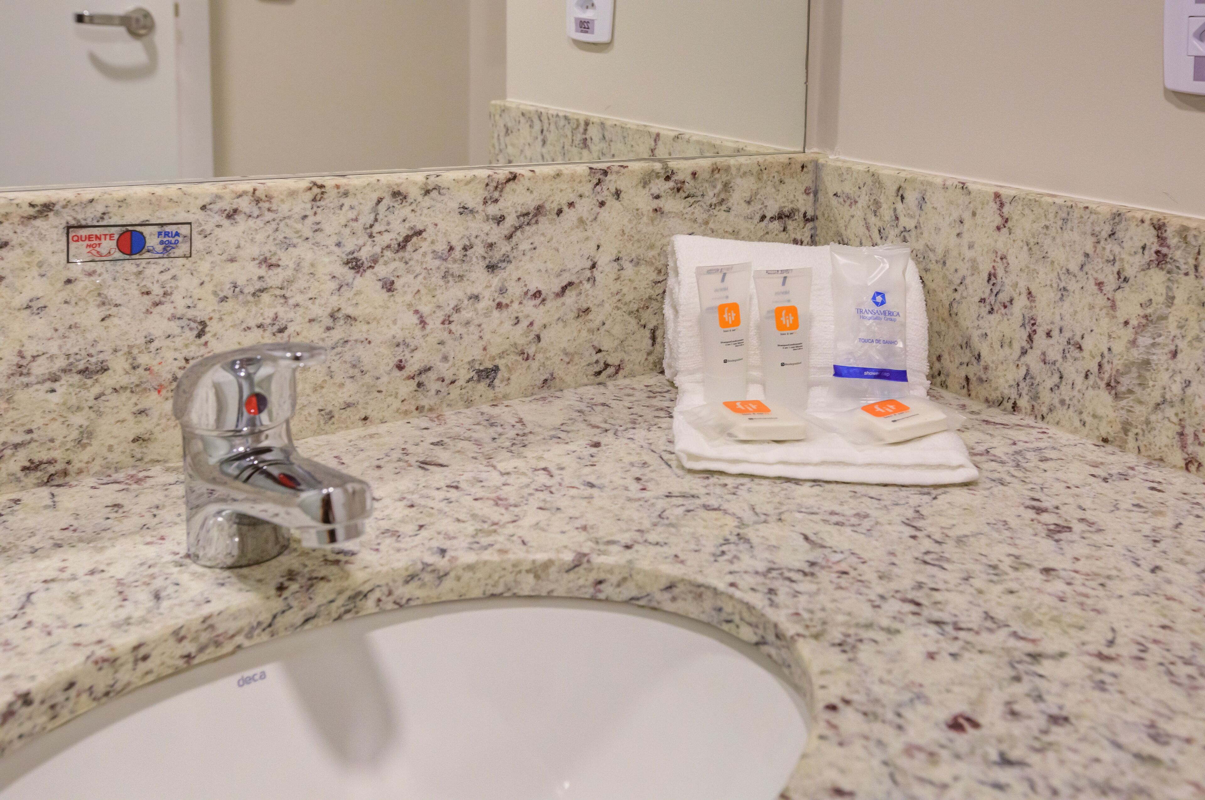 A bathroom with a granite countertop, a sink, a faucet, and toiletries including a toothbrush and toothpaste.