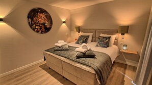 Un dormitorio moderno con una cama grande, dos mesitas de noche y una obra de arte colgada en la pared.