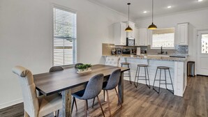 Uma cozinha moderna com armários brancos, bancada de madeira e iluminação pendente.