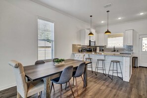 Enjoy meals in the kitchen with a central island and dining area featuring a wooden table and pendant lighting.