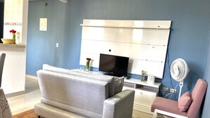A living room with a grey sofa, a television, a white cabinet, and a pink chair. - Beautiful and cozy apartment in Mompós (Santa Cruz de Mompox)