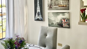 A dining area with a table set for two, a potted plant, and wall art depicting famous landmarks. - Beautiful and cozy apartment in Mompós (Santa Cruz de Mompox)