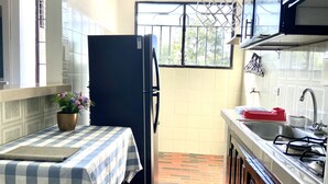A compact kitchen with a refrigerator, sink, and a small dining area with a checkered tablecloth. - Beautiful and cozy apartment in Mompós (Santa Cruz de Mompox)