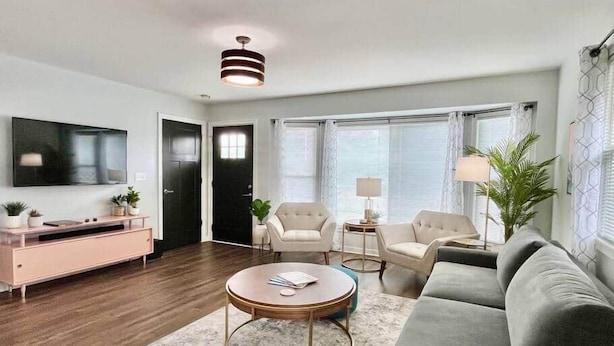 A modern living room with a sofa, armchairs, a coffee table, a TV, and a console table. - Sunsets on the Grand (Lansing)