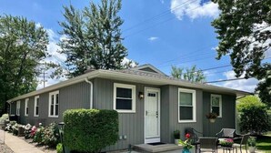 A single-story house with a front porch, a small garden, and a clear sky. - Sunsets on the Grand (Lansing)