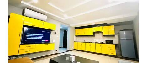A modern kitchen with yellow cabinets and a black countertop.