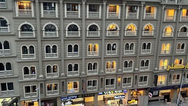 Ein mehrstöckiges Hotel im klassischen Baustil, mit Balkonen und einem zentralen Eingang mit einem Schild.