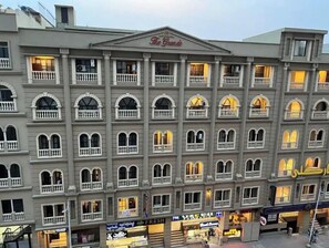 A multi-story hotel with a classic architectural style, featuring balconies and a central entrance with a sign.