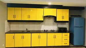 Eine Küche mit gelben Schränken, einer schwarzen Arbeitsplatte und einem blauen Kühlschrank.