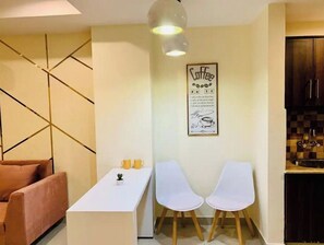 Cozy living space with a dining table for two, kitchenette, and pendant light.