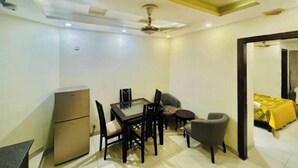 Un espacio habitable compacto con zona de comedor, una kitchenette pequeña y un dormitorio con cama cubierta por un edredón amarillo.