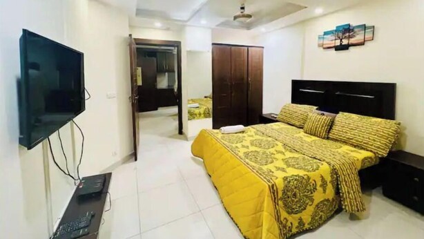 Un dormitorio con cama, televisión, armario y ventilador de techo.