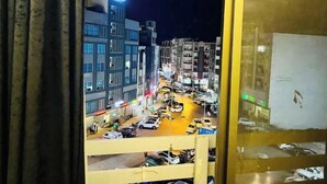 A nighttime view of a city street with buildings and parked cars. - The Red one bedroom apartment in bahria town (Rawalpindi)