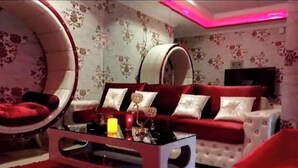 A living room with a red sofa, a round chair, and a glass coffee table. - The Red one bedroom apartment in bahria town (Rawalpindi)