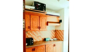 A kitchen with wooden cabinets, a microwave, and a tiled backsplash. - The view apartment in Bahria town. (Rawalpindi)