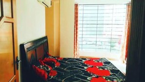 A bedroom with a bed, a window with curtains, and an air conditioning unit. - The view apartment in Bahria town. (Rawalpindi)