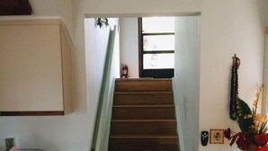 A staircase leading to a second floor, a kitchen area with a countertop and cabinets, and a small table with a vase of flowers. - #25 Colony One at Sea Mt. Punalu`u (Pahala)