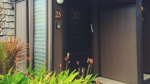 A modern building with a covered entrance, a number '25' sign, and a small garden area with plants in the foreground. - #25 Colony One at Sea Mt. Punalu`u (Pahala)