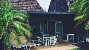 A patio with a table and chairs, surrounded by a lawn and palm trees. - #17 Colony One at Sea Mt. Punalu`u (Pahala)