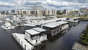 Una marina con case galleggianti, un molo e uno skyline sullo sfondo.