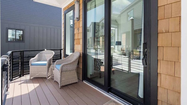 Un balcone con sedie in vimini e una porta vetrata che dà su un patio.