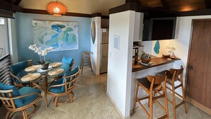 Un coin repas avec une table ronde, des chaises bleues et un luminaire suspendu.