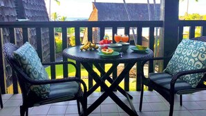 Un balcon avec une table dressée pour deux personnes, offrant une vue tropicale sur les palmiers.