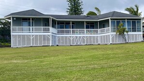 A two-story house with a covered porch and a fenced yard. - 2 Bedroom / 2 Bath Home on Golf Course with Stunni (Naalehu)