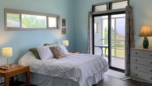 A bedroom with a bed, two bedside tables with lamps, a ceiling fan, a window, and a sliding glass door leading to a balcony. - 2 Bedroom / 2 Bath Home on Golf Course with Stunni (Naalehu)