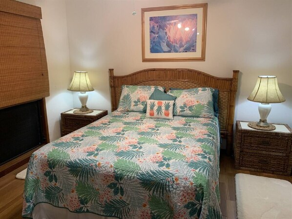 Un dormitorio con cama, dos mesitas de noche con lámparas, un cuadro en la pared y una ventana con persianas.