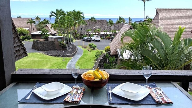 A dining table with a view of a tropical resort, including palm trees and a clear sky. - #56 Colony One at Sea Mt. Punalu`u (Pahala)