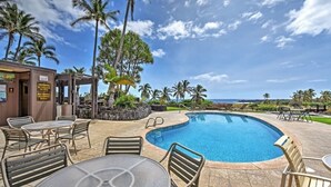 A pool area with lounge chairs and tables, surrounded by palm trees and a view of the ocean. - #04 Rest & Relax at Punalu`u Black Sand Beach (Pahala)