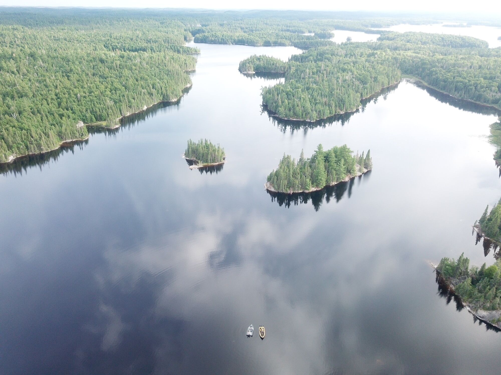 An aerial view of a lake surrounded by dense forests with several small islands.