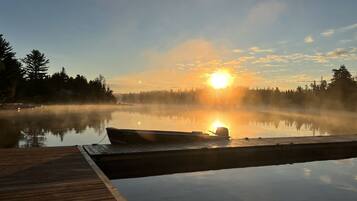 A wooden dock extending into a calm lake with a boat moored at the end.
