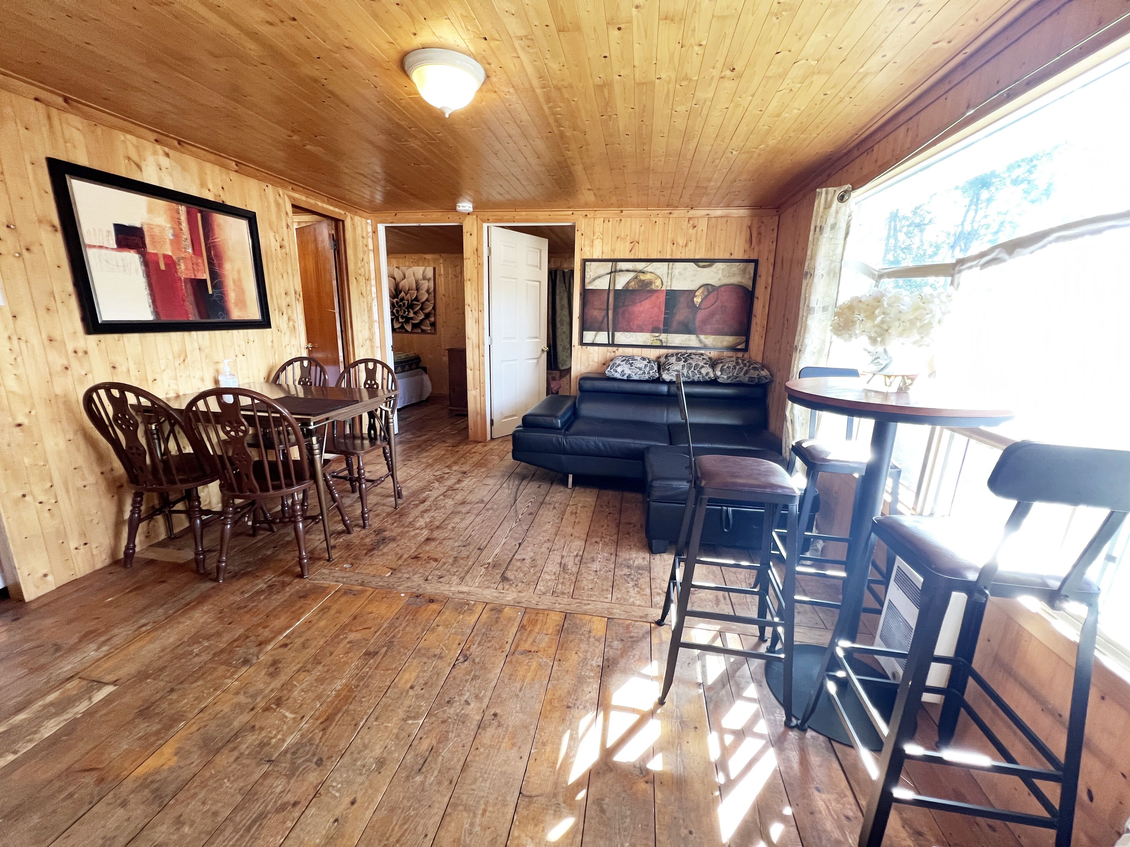 A wooden interior with a dining area, a sofa, and a bar.
