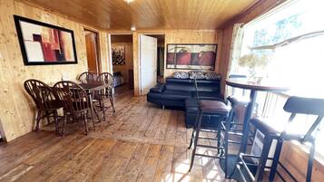A wooden interior with a dining area, a sofa, and a bar.