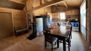 A wooden cabin interior with a dining area, kitchen, and a cozy seating area. - Lake Onaping Lodge (Unorganized North Sudbury)