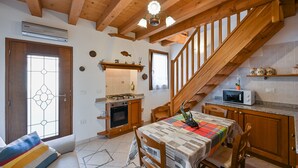 A cozy kitchen with wooden beams, a dining table with a colorful tablecloth, and a staircase. - Pink Paradise (Venezia)