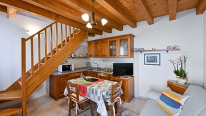 A cozy kitchen with wooden cabinets, a dining table, and a staircase. - Pink Paradise (Venezia)