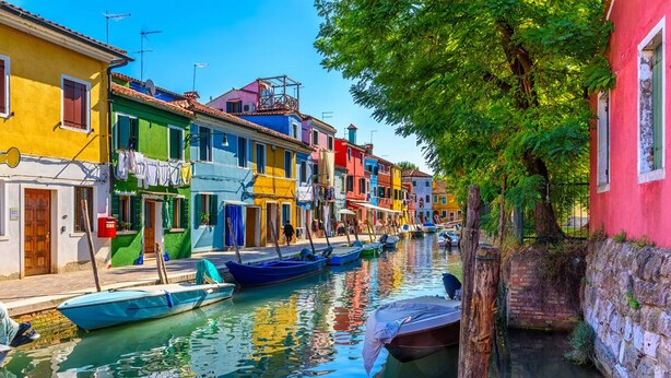 A canal lined with colorful buildings, boats docked along the water, and a narrow path on the right. - Pink Paradise (Venezia)