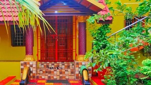 A colorful building with a red door, tiled steps, and a palm tree.