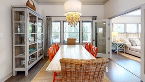 A dining area with a long wooden table, red chairs, a chandelier, and a wicker basket. - Seabrook Exclusives | 2717 Seabrook Island Rd (Seabrook Island)